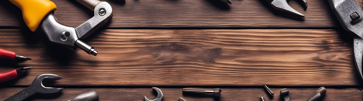 The image shows a set of tools including a wrench, screwdriver, pliers, and hammer on a wooden workbench in a workshop.